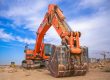 Orange excavator with digging bucket ready for work on a construction site