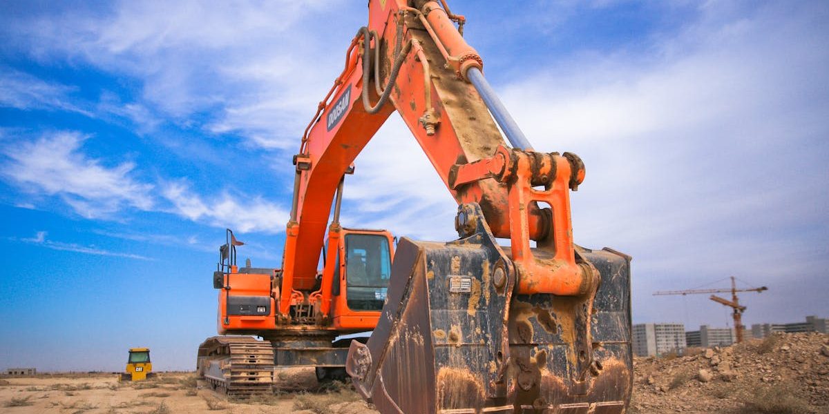 Orange excavator with digging bucket ready for work on a construction site