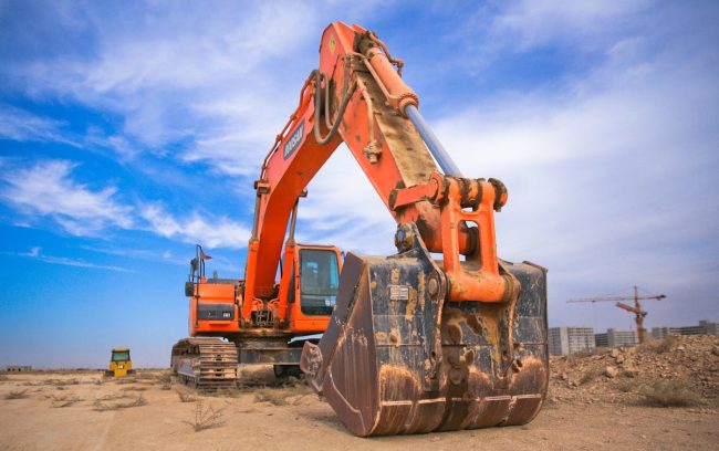 Orange excavator with digging bucket ready for work on a construction site